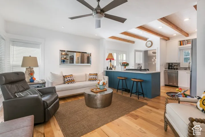 Hardwood flooring throughout, exposed wood beams, and a ceiling fan with integrated lighting