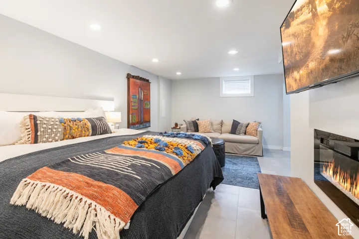 Recessed lighting, wall-mounted television, built-in electric fireplace, light-toned walls, and tile flooring
