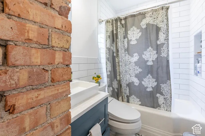 Exposed brick wall detail, subway tile walls, built-in bathtub, vessel sink, and a built-in vanity with storage