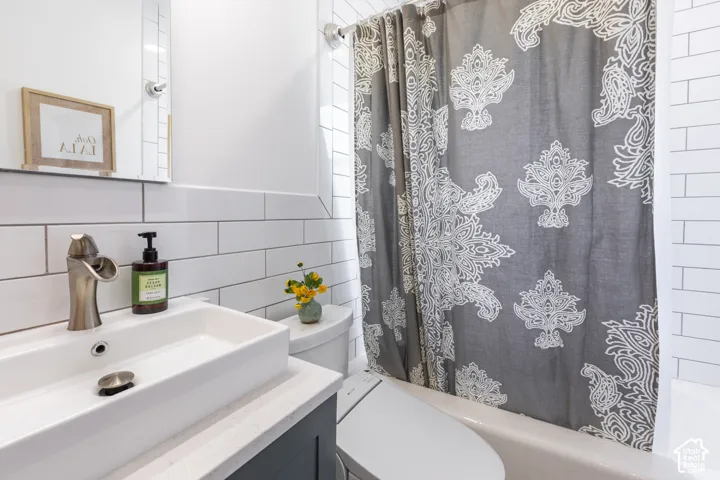 White subway tile, rectangular vessel sink, brushed nickel faucet, light-toned countertop, and built-in bathtub