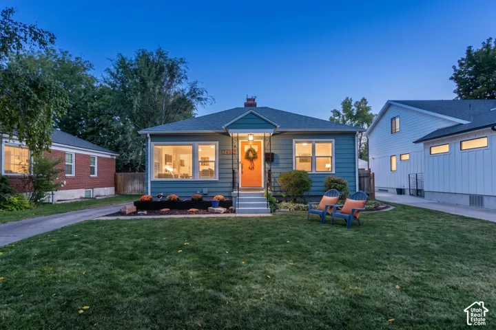 Single-story home featuring a covered front entry with an orange door, a well-maintained lawn, and a paved driveway