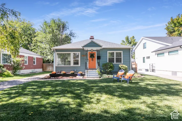 Exterior siding, brick chimney, gabled roof, front porch with columns, and a landscaped yard