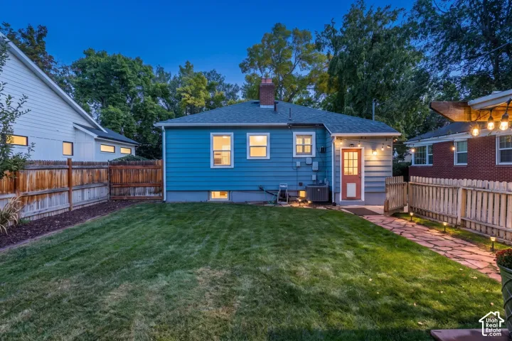 Expansive lawn with a stone pathway, privacy fencing, and a detached structure with a red entry door