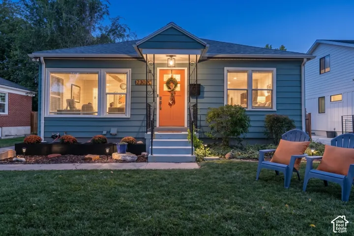 Siding exterior with a covered entry, vibrant orange front door, and symmetrical front windows
