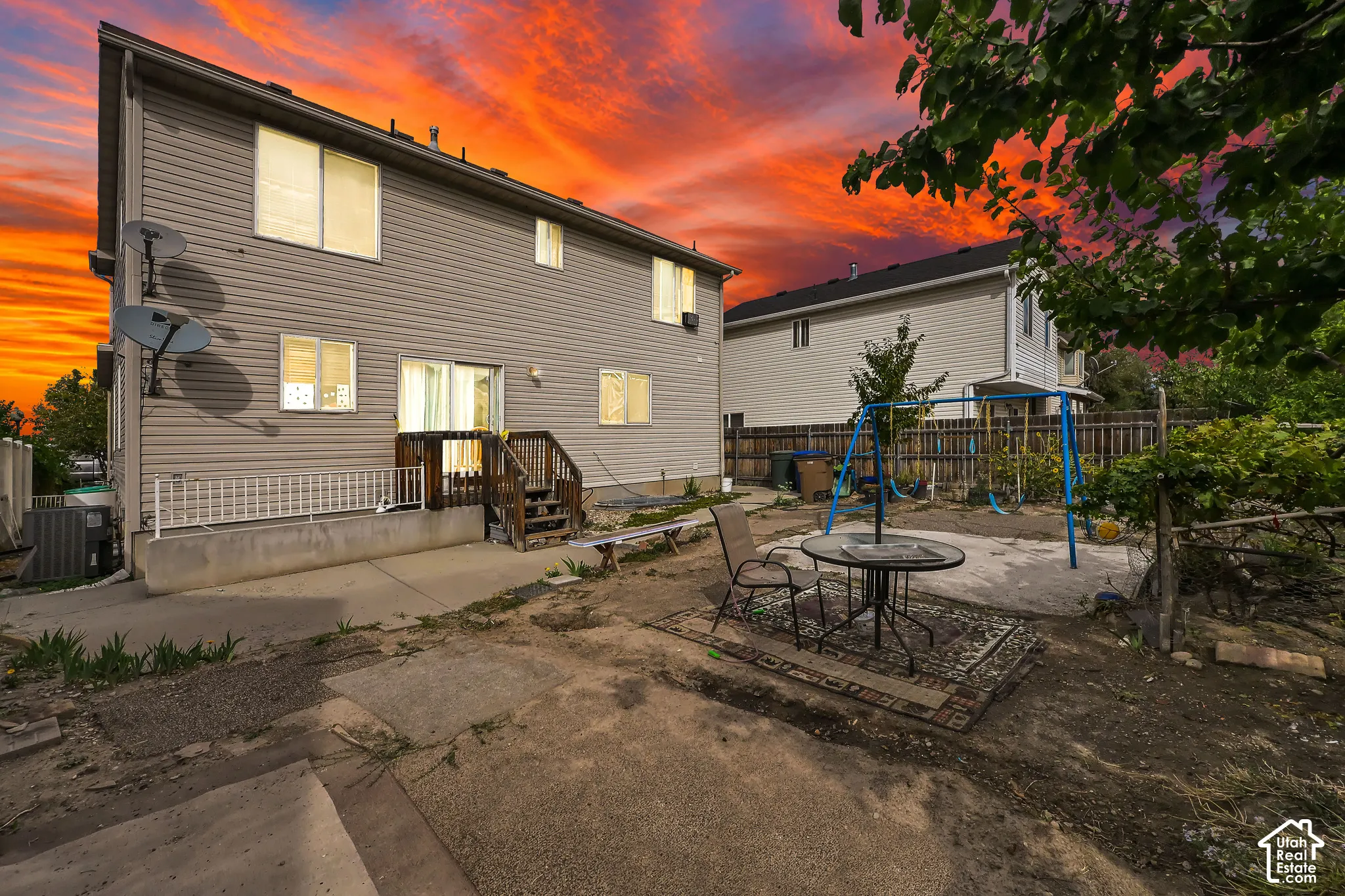 Rear exterior featuring horizontal siding, ground-level concrete patio, and upper-level wood deck with stairs