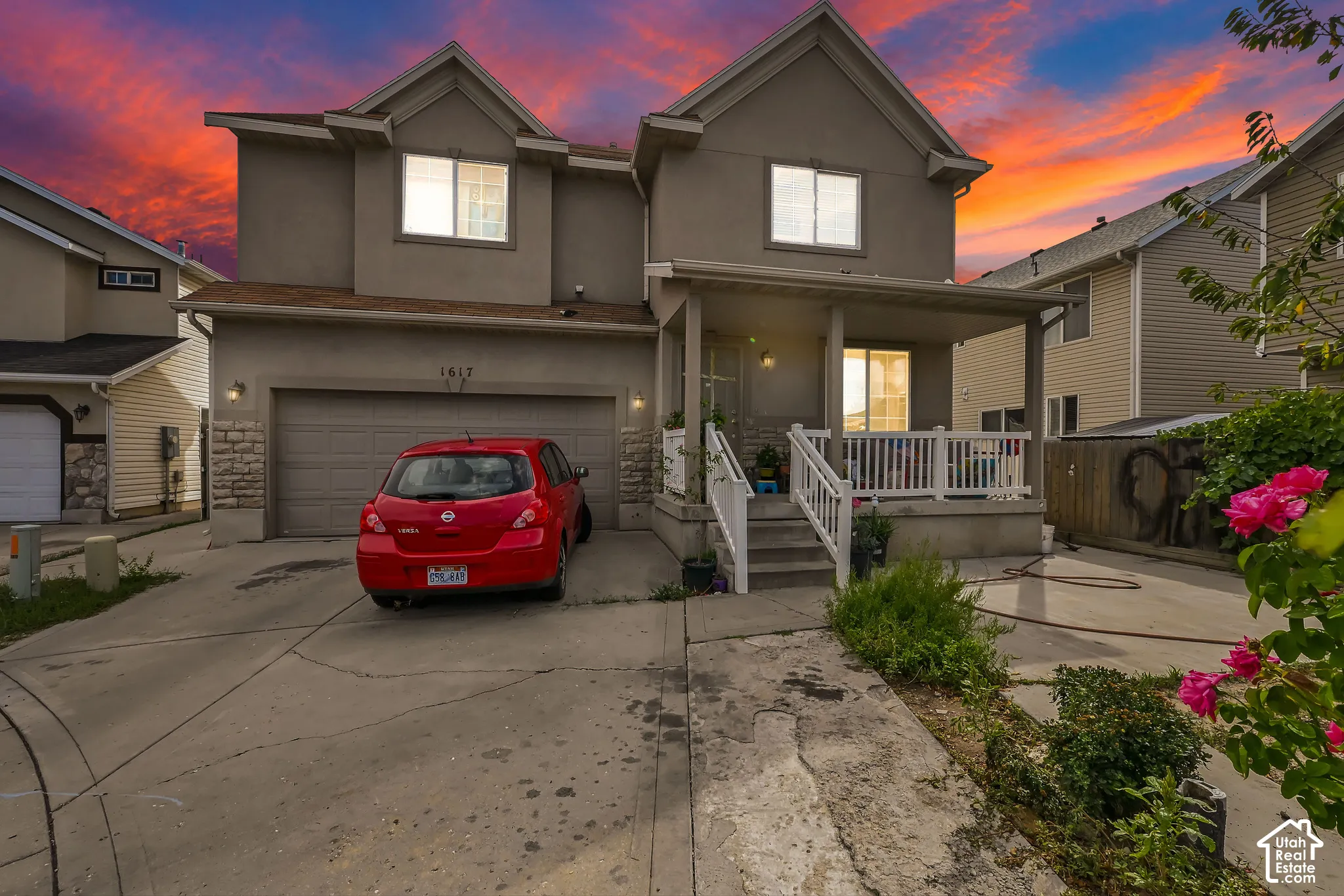 Stucco exterior with stone accent detailing, covered front porch, attached garage, and concrete driveway