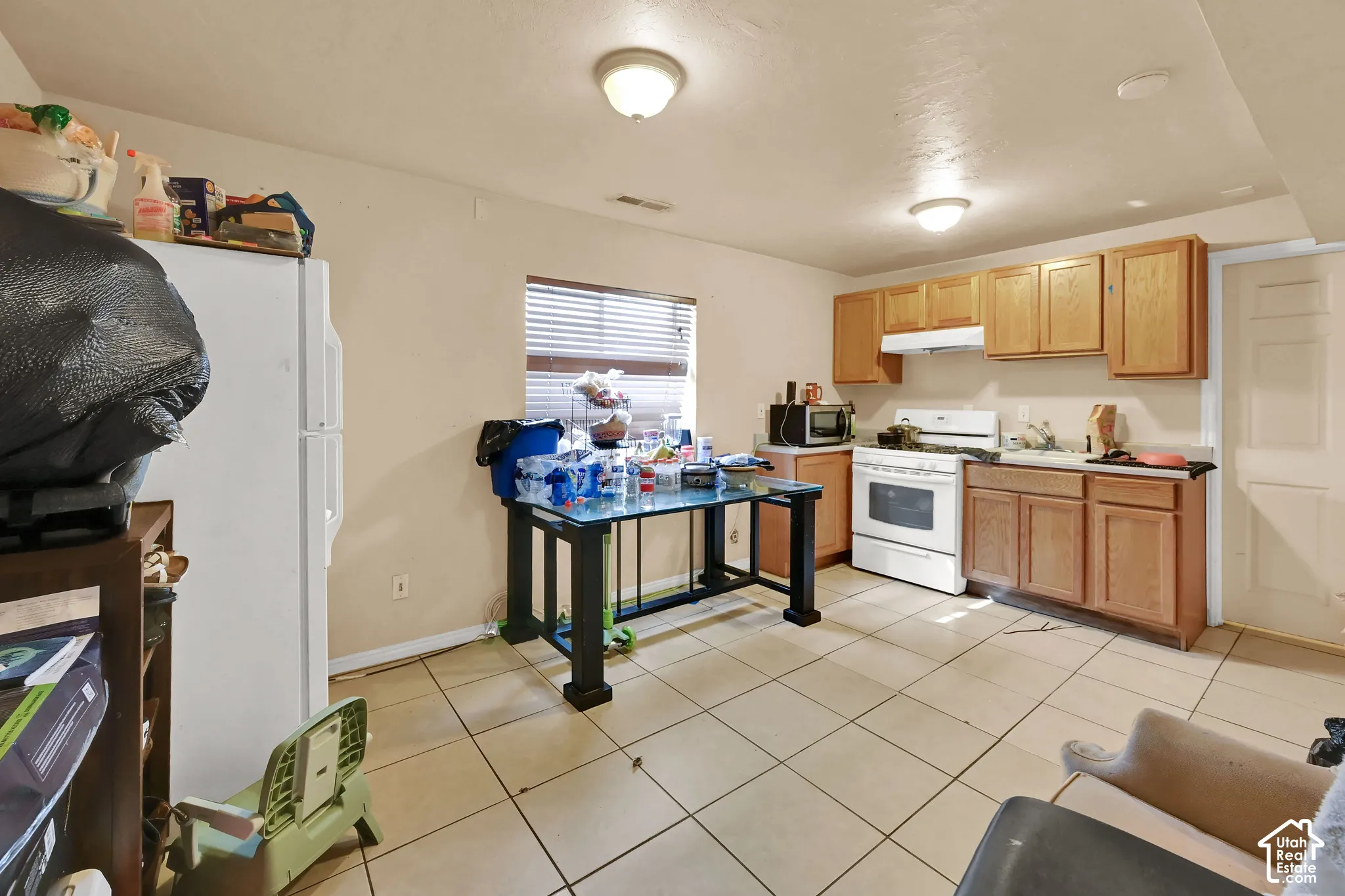 Kitchen featuring wood-finish cabinetry, white appliances, and a tiled floor