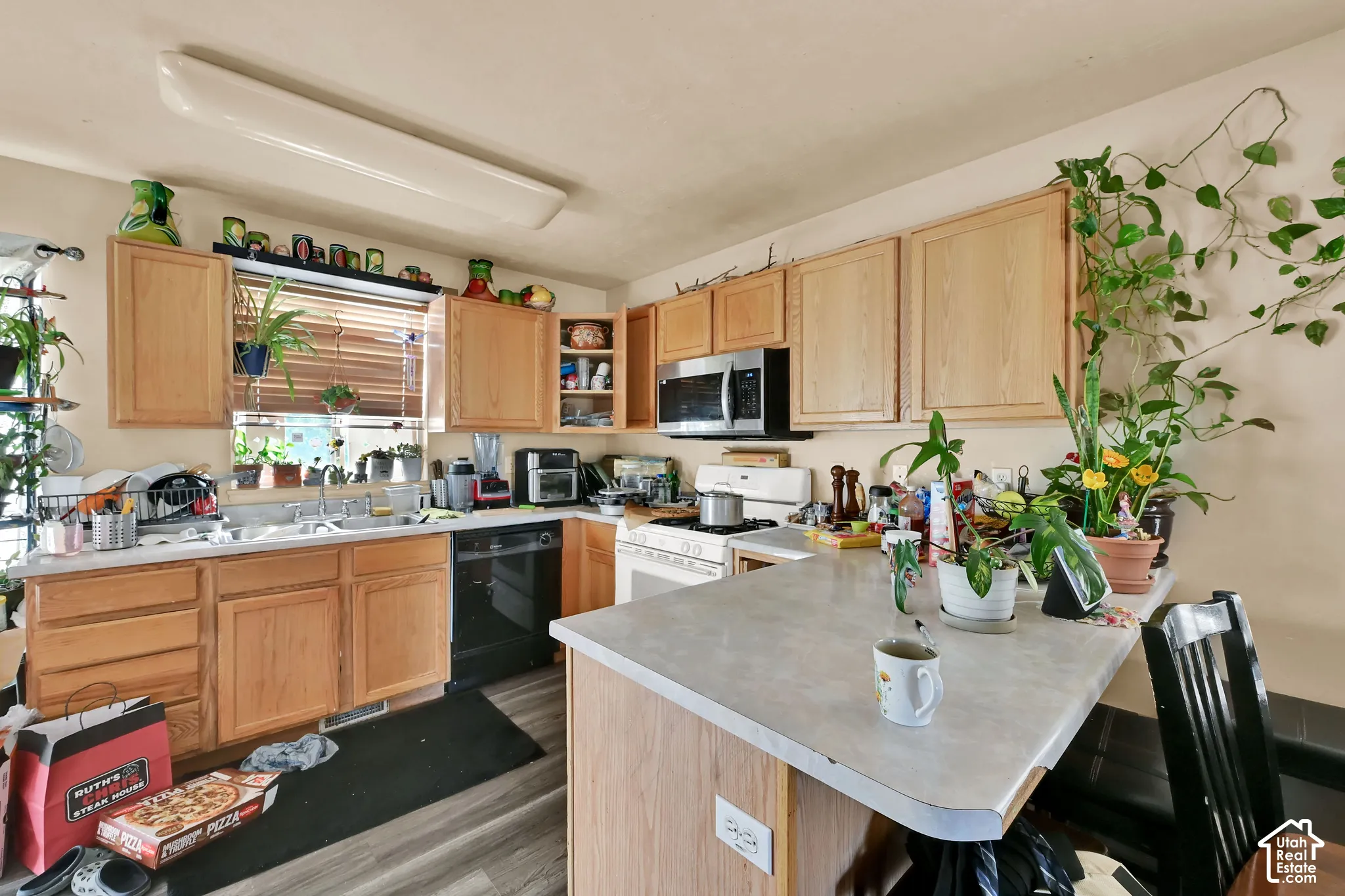 Kitchen featuring wood-finish cabinetry, stainless steel microwave, black dishwasher, and a center island with countertop seating