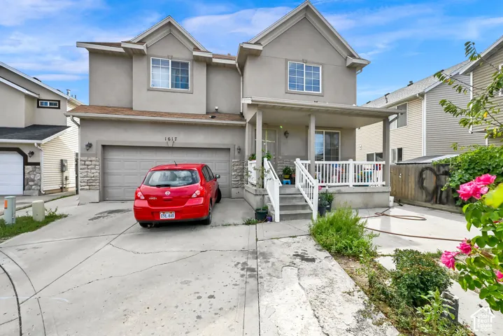 Contemporary stucco exterior with a covered porch and white railing, featuring a single-car garage and a paved driveway