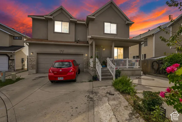 Stucco exterior with stone accent detailing, covered front porch, attached garage, and concrete driveway