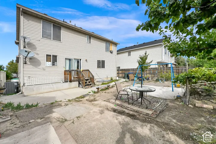 Rear exterior with horizontal siding, a ground-level patio, and an upper-level deck with wood stairs