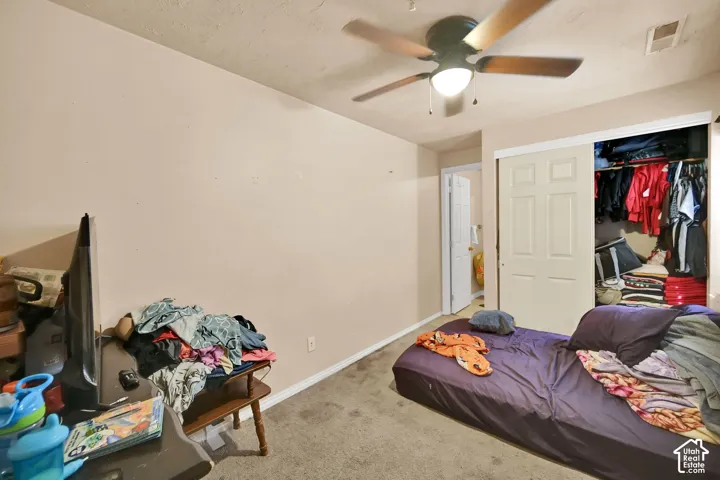 Room featuring carpeted flooring, a ceiling fan with integrated lighting, and a closet with bi-fold doors