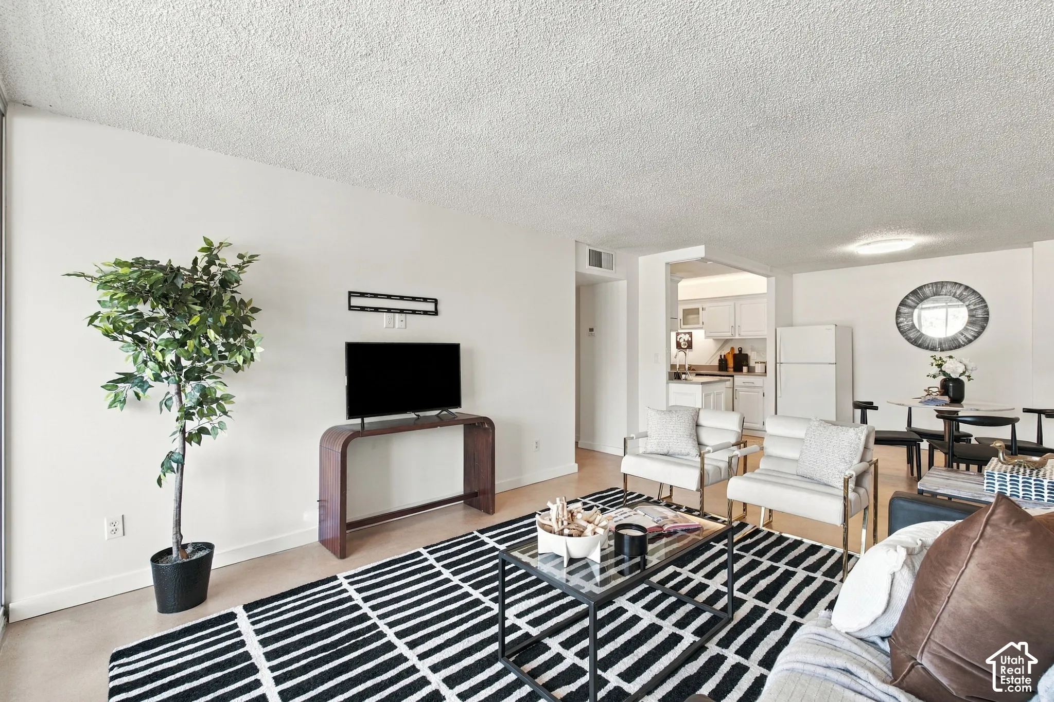 Open-concept living area with light-toned flooring and white walls