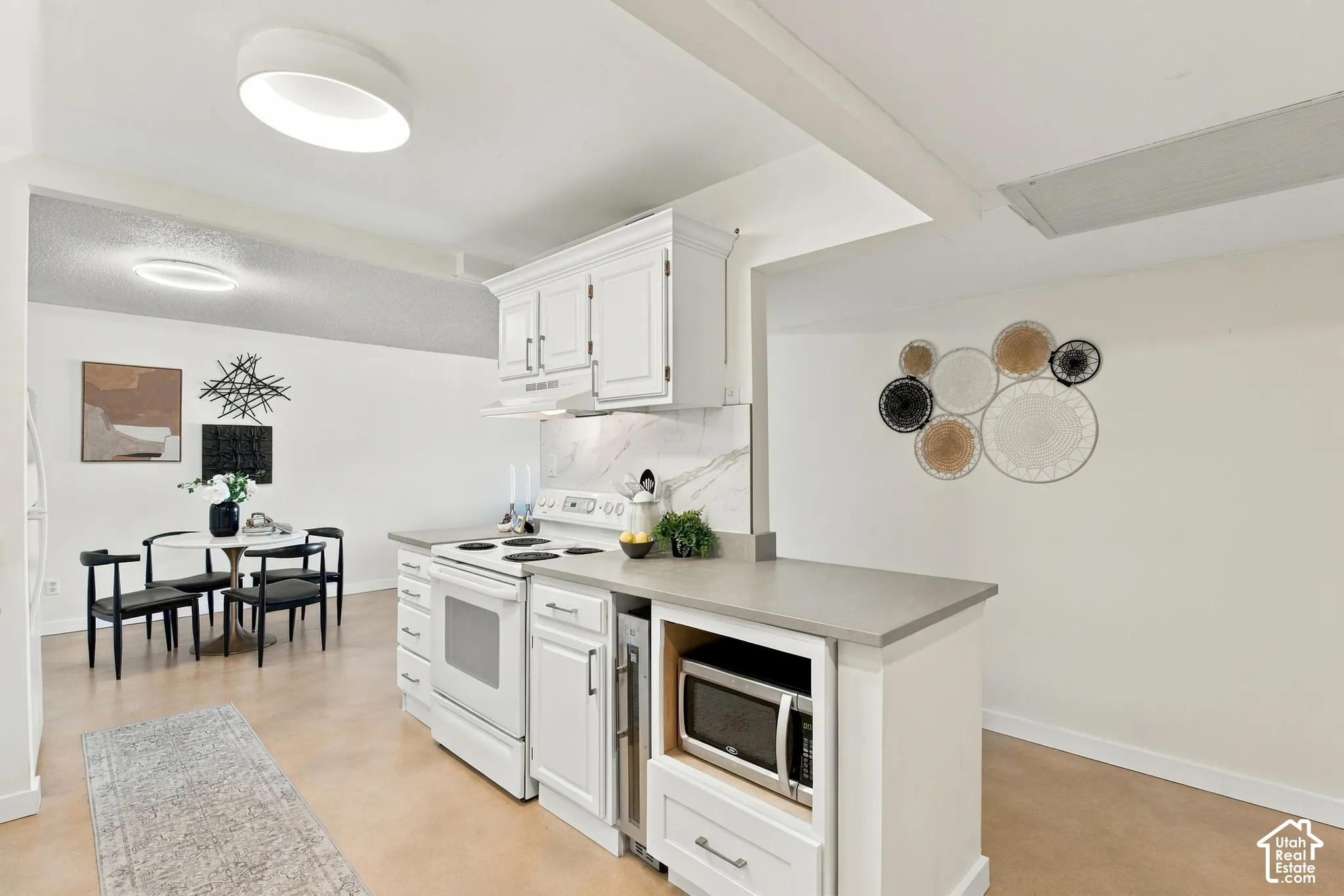 White cabinetry with upper and lower storage, stone-finish countertops, built-in microwave, and electric range