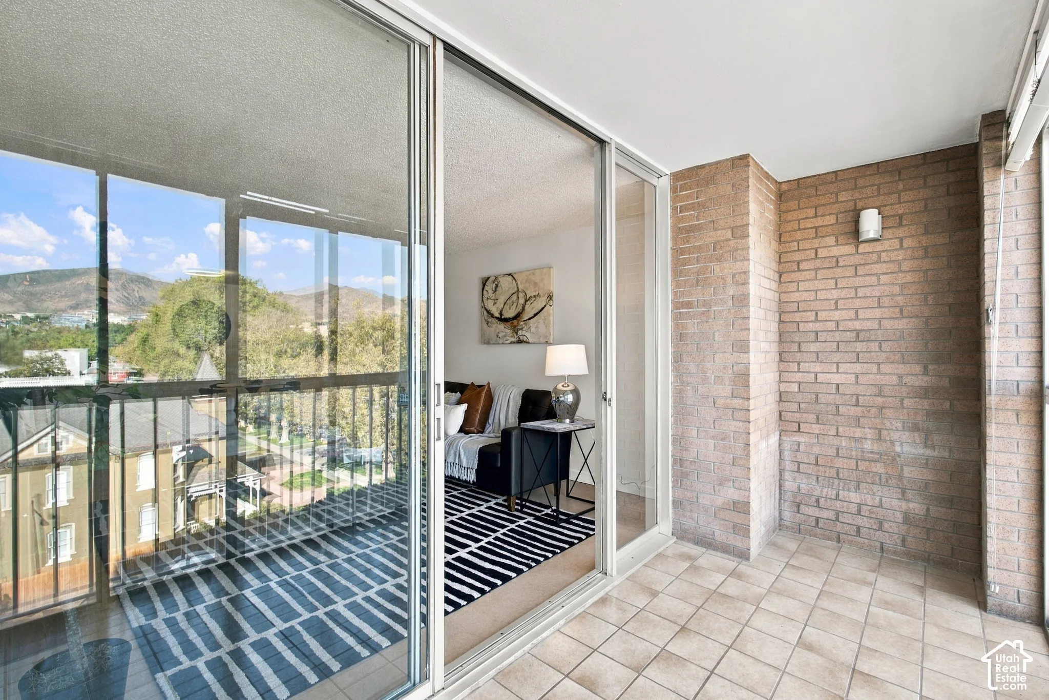 Balcony with tiled flooring, brick walls, and mountain scenery