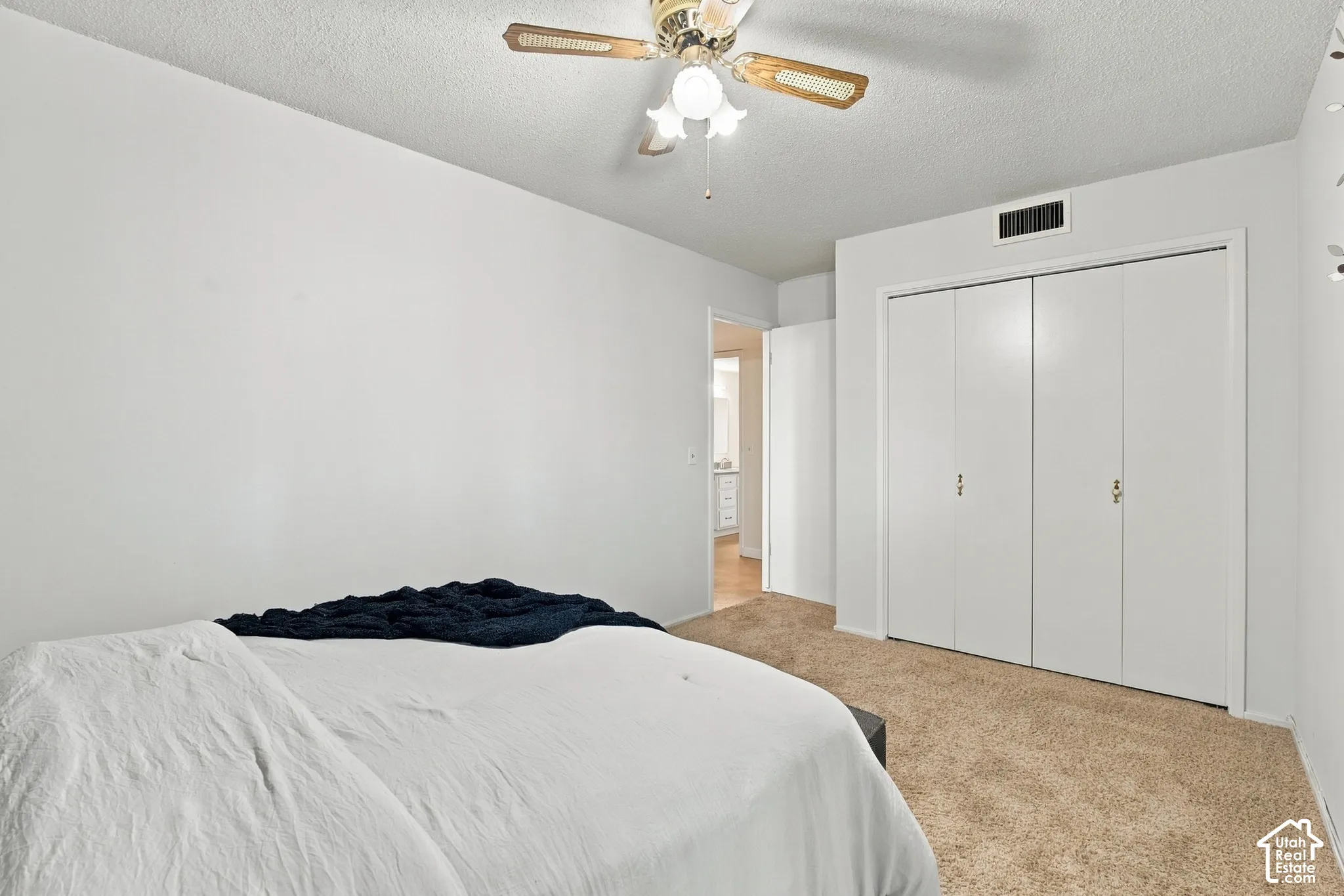 Carpeted room featuring a ceiling fan with light fixture and bi-fold closet doors