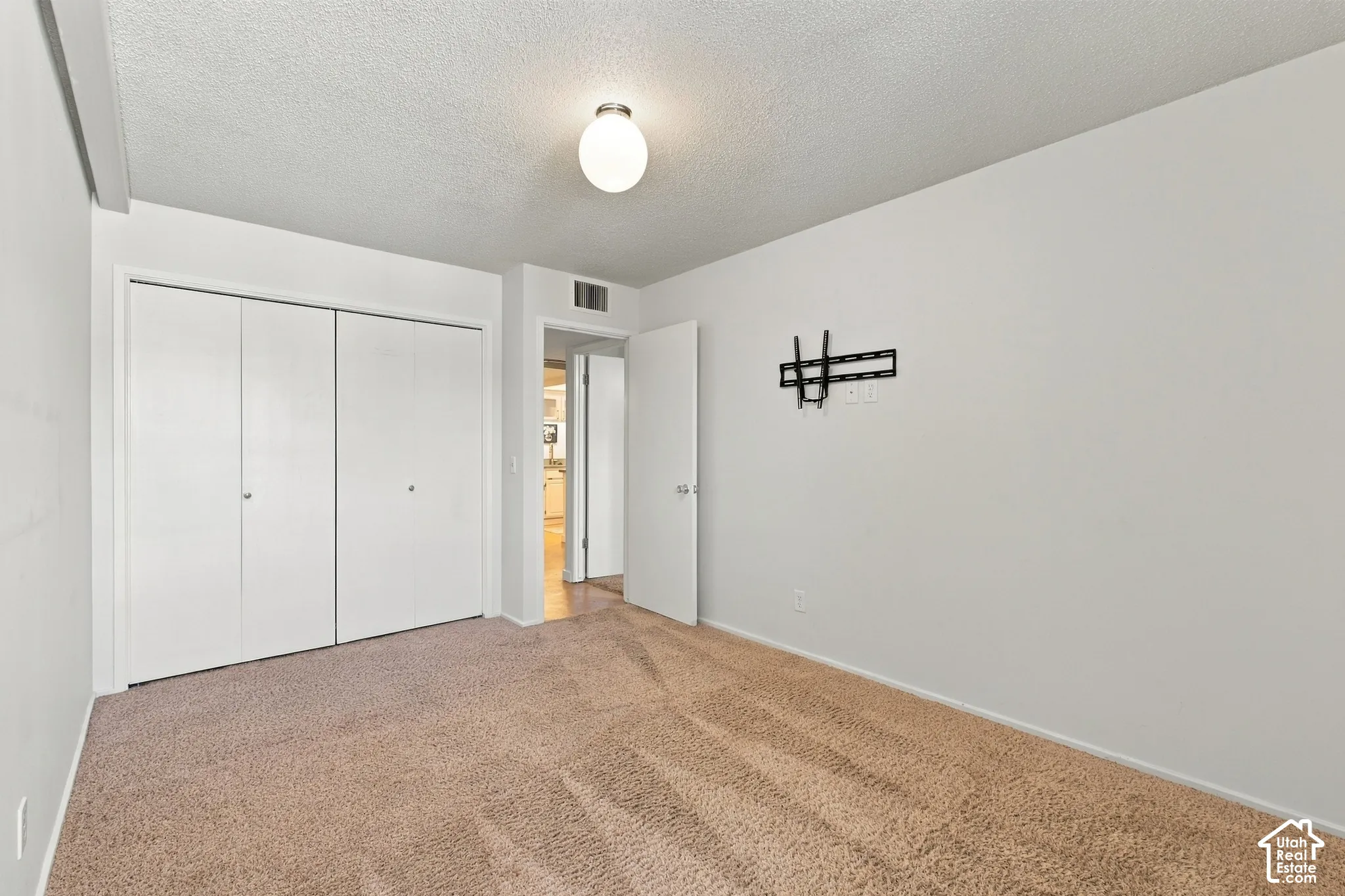 Spacious bedroom with neutral wall finishes, recessed lighting, and double closet doors with white frames