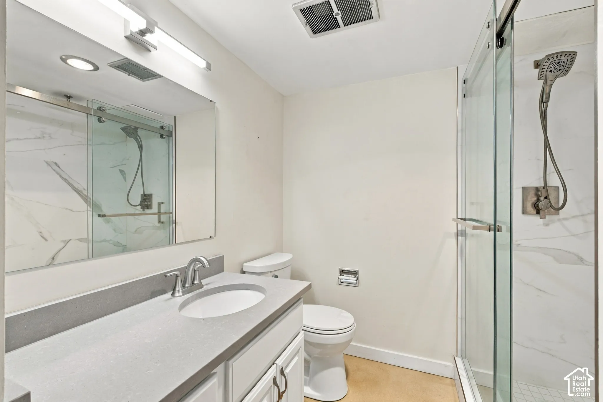 Bathroom featuring a single vanity with gray countertop, undermount sink, and brushed nickel faucet