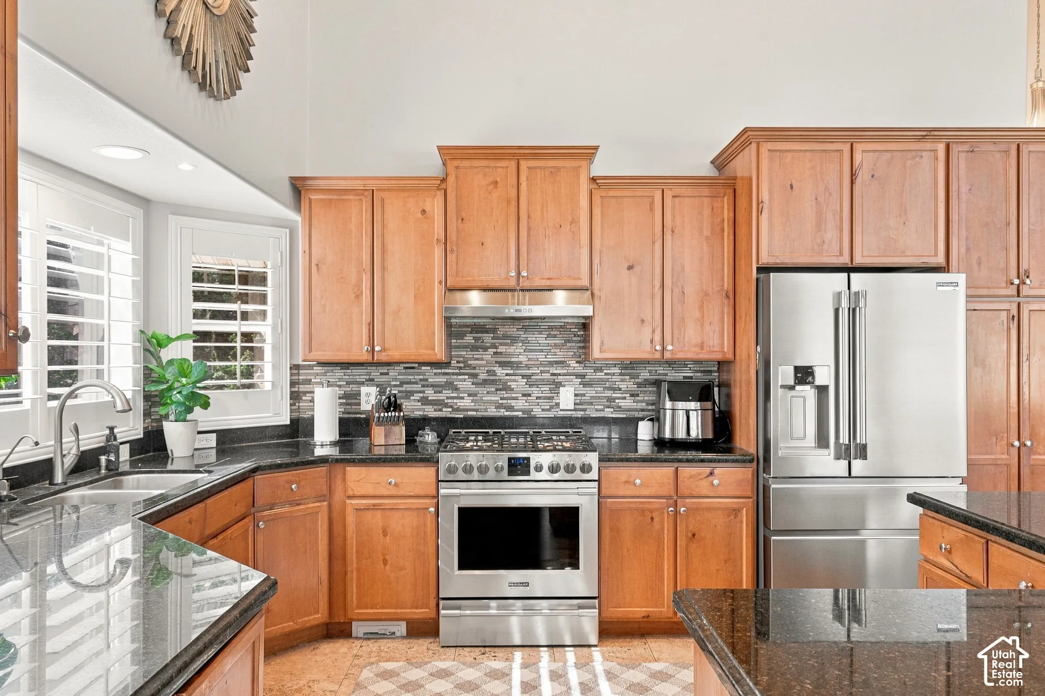 Kitchen featuring wood cabinetry, stainless steel appliances, dark stone countertops, and a tile backsplash