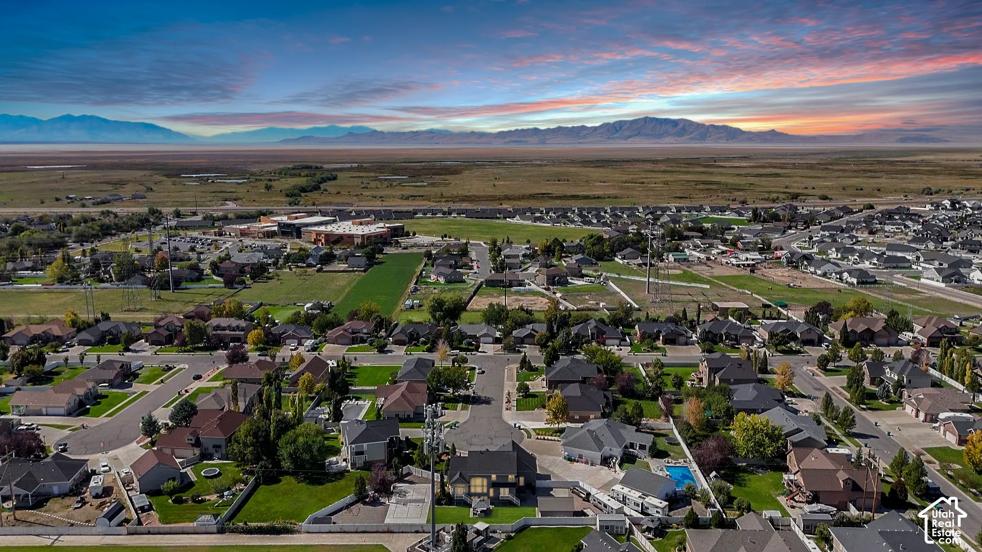 Residential neighborhood with established homes and landscaped yards, bordered by open land