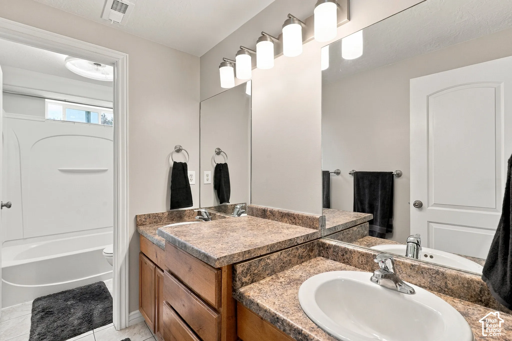 Dual vanity with integrated sinks, wood-finish cabinetry, and a full-width mirror