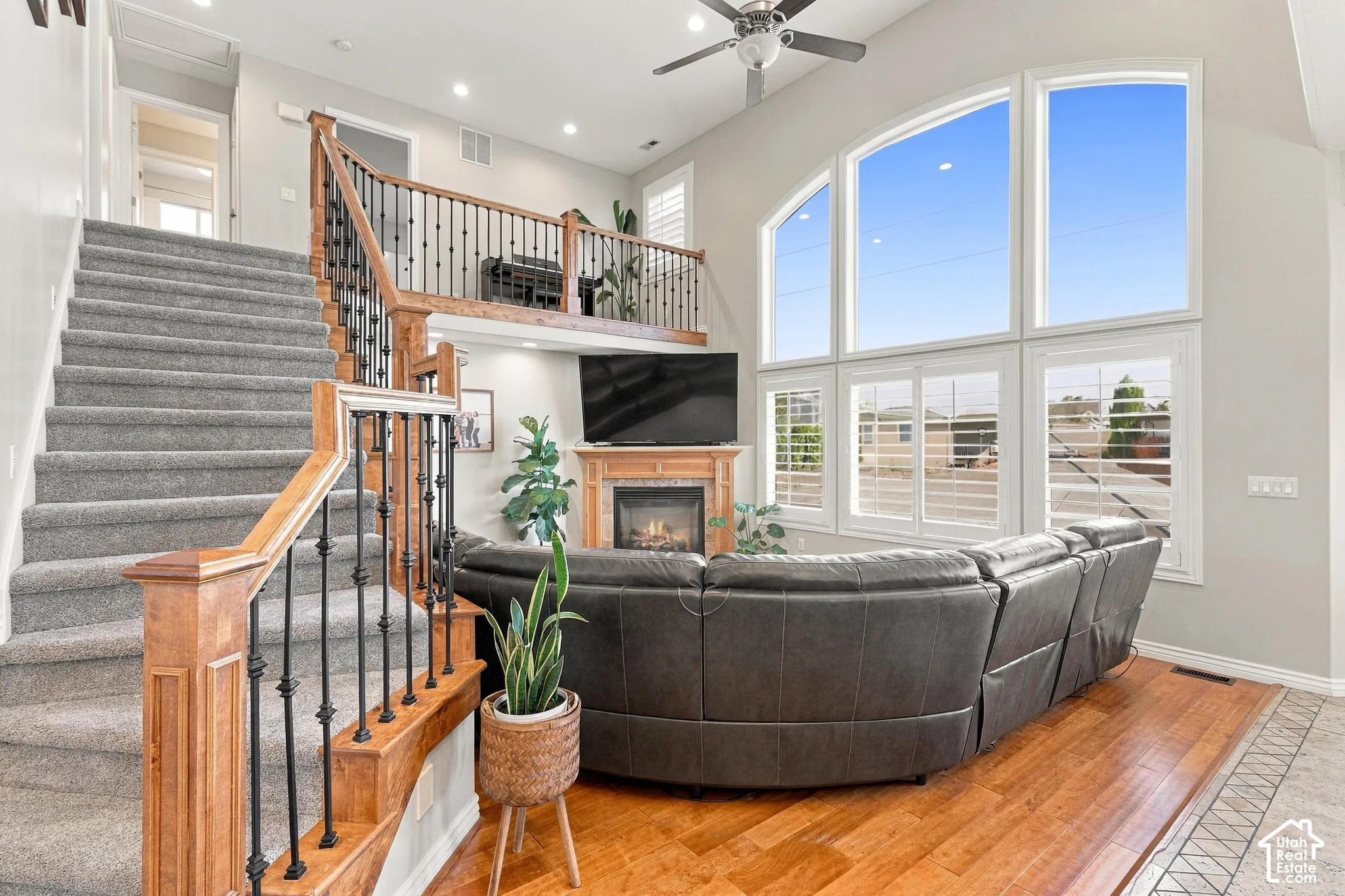 Two-story living area with a gas fireplace, a wood mantel, and an arched window arrangement
