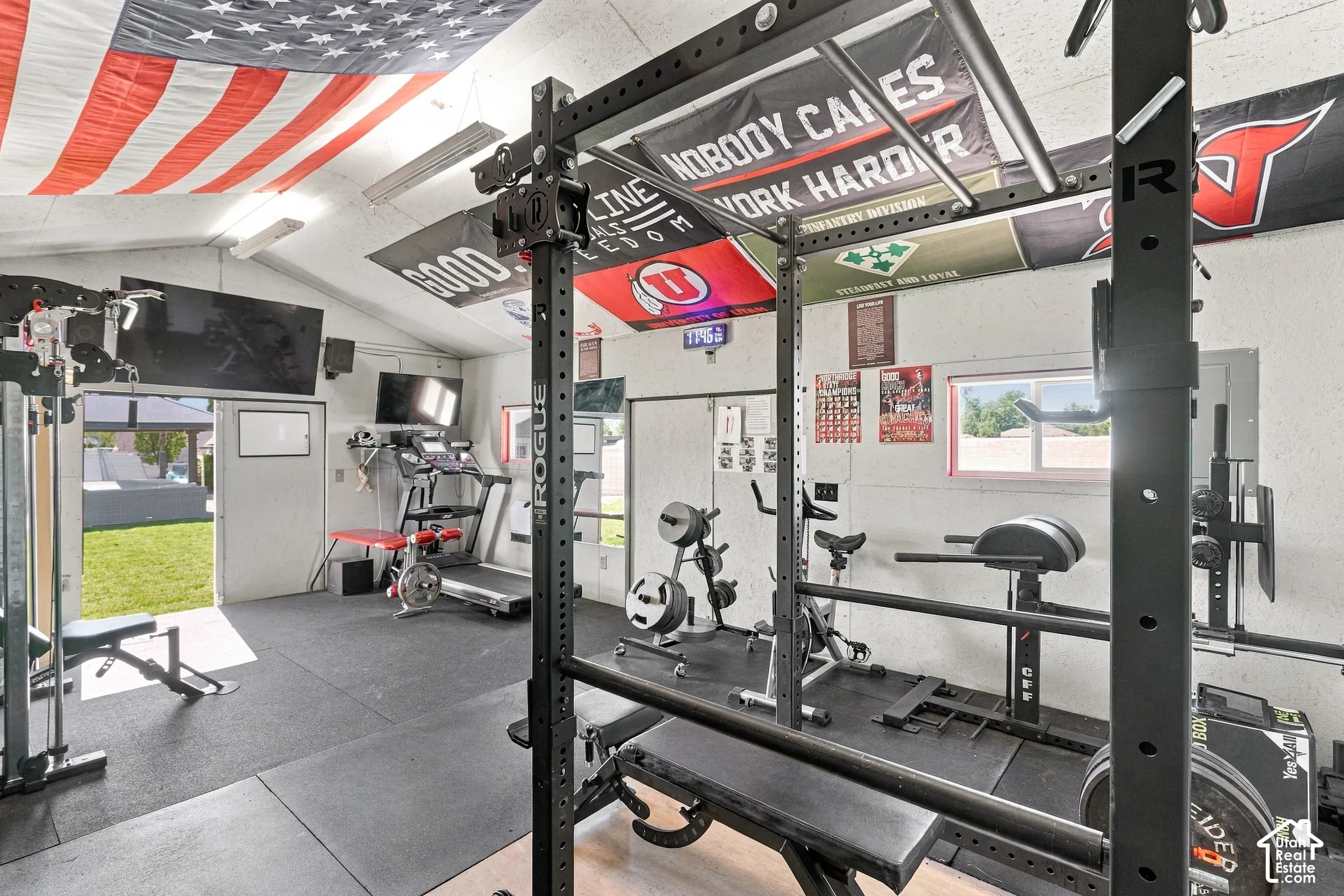 Dedicated fitness space featuring rubber flooring, exposed ceiling beams, and multiple windows for natural light