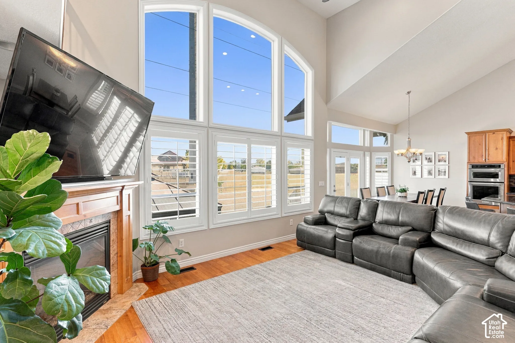 Two-story vaulted ceilings, wood-finish flooring, and a fireplace with a wood mantle