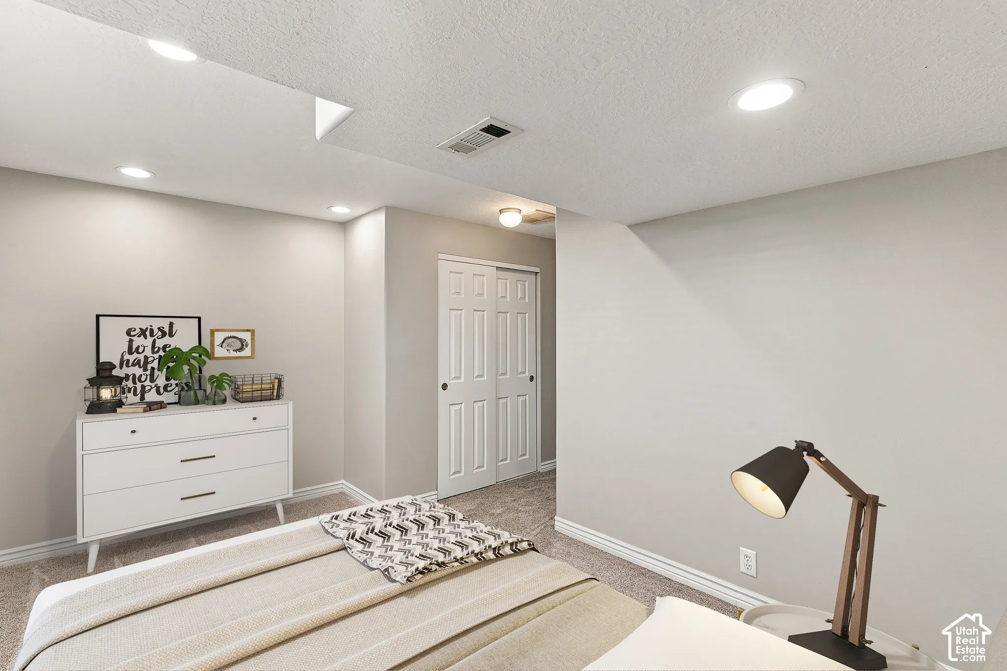 Recessed lighting, neutral wall paint, carpeted flooring, and a sliding two-panel door