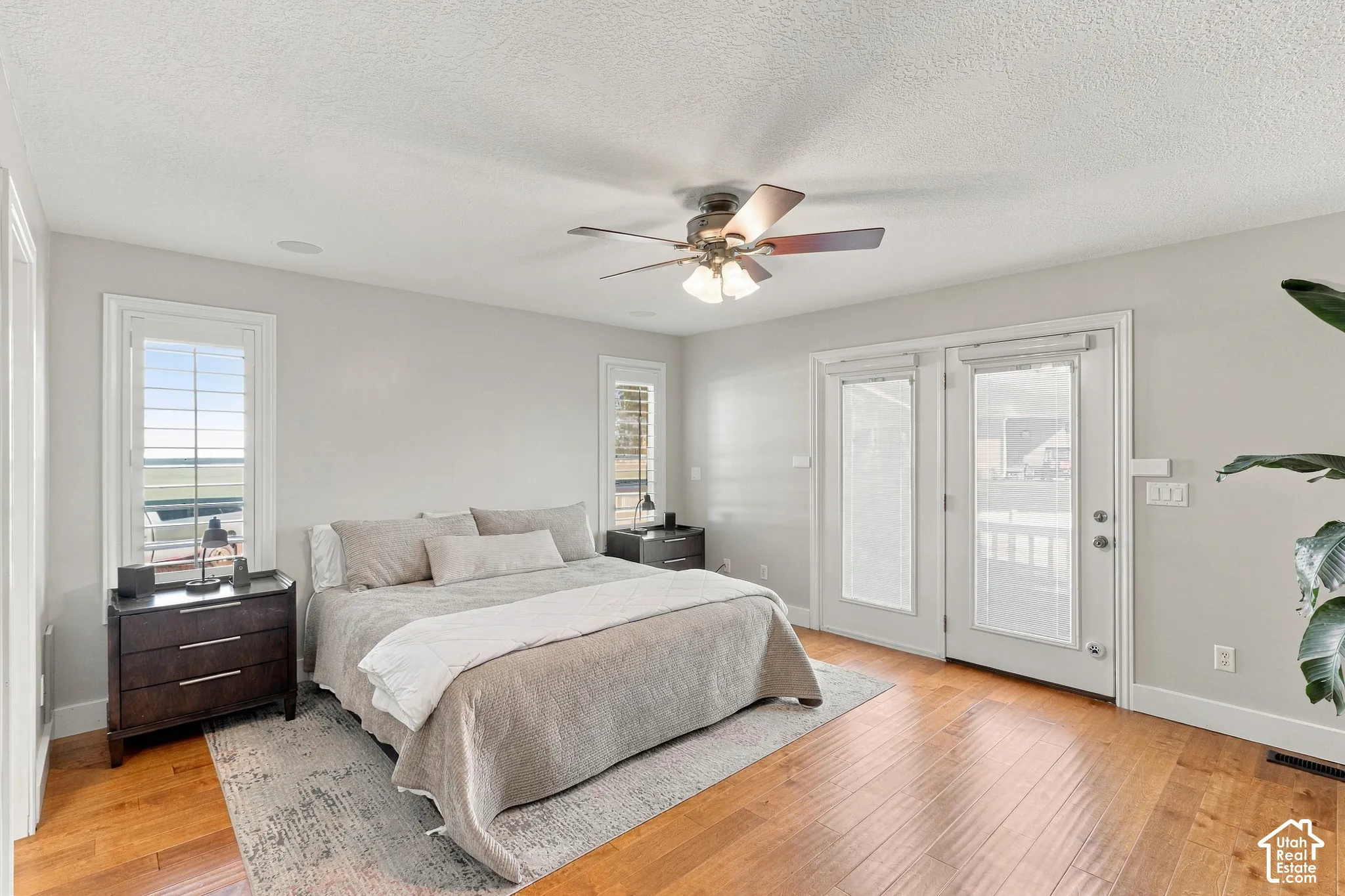 Hardwood flooring, plantation shutters, ceiling fan with integrated lighting, and white French doors