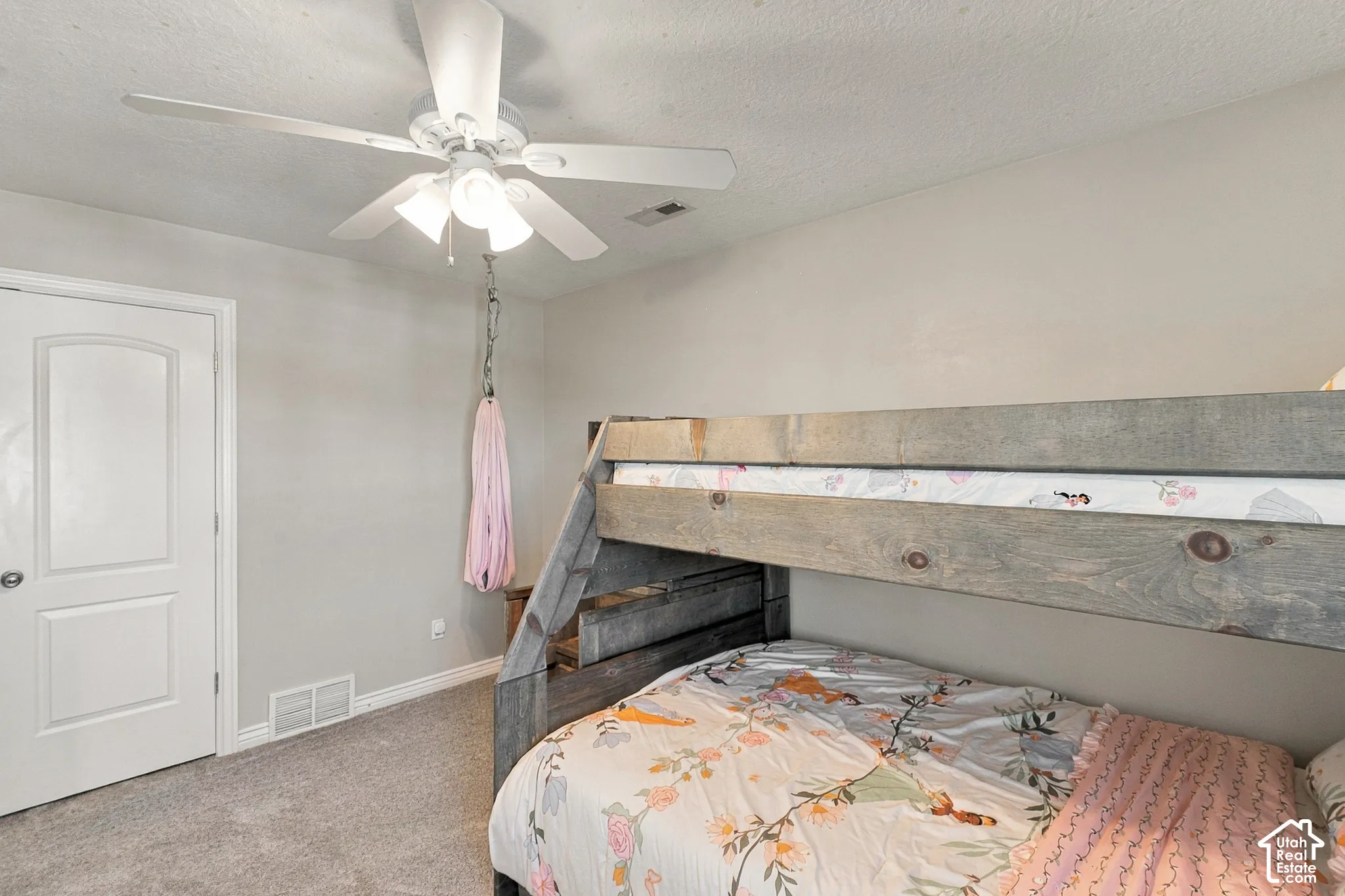 Neutral wall color, ceiling fan with integrated lighting, door with panel detailing, and gray carpet flooring