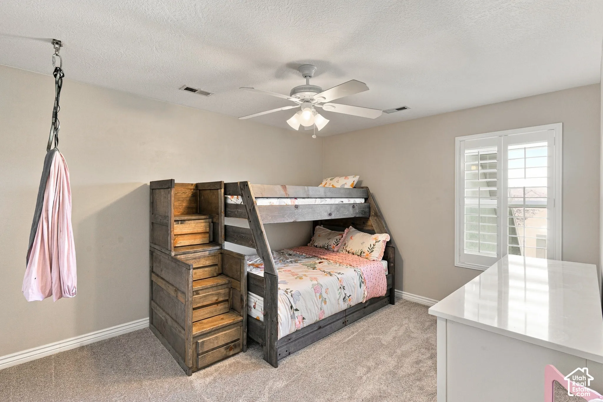 Carpeted room featuring a ceiling fan, white window shutters, and built-in bunk bed with integrated staircase