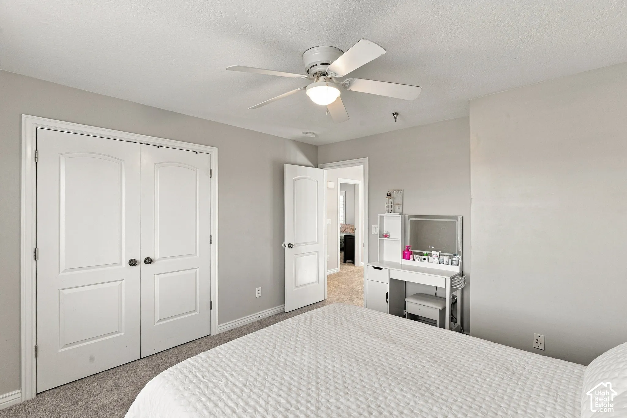 Carpeted flooring, white bi-fold doors with dark hardware, ceiling fan with integrated lighting, and neutral wall paint