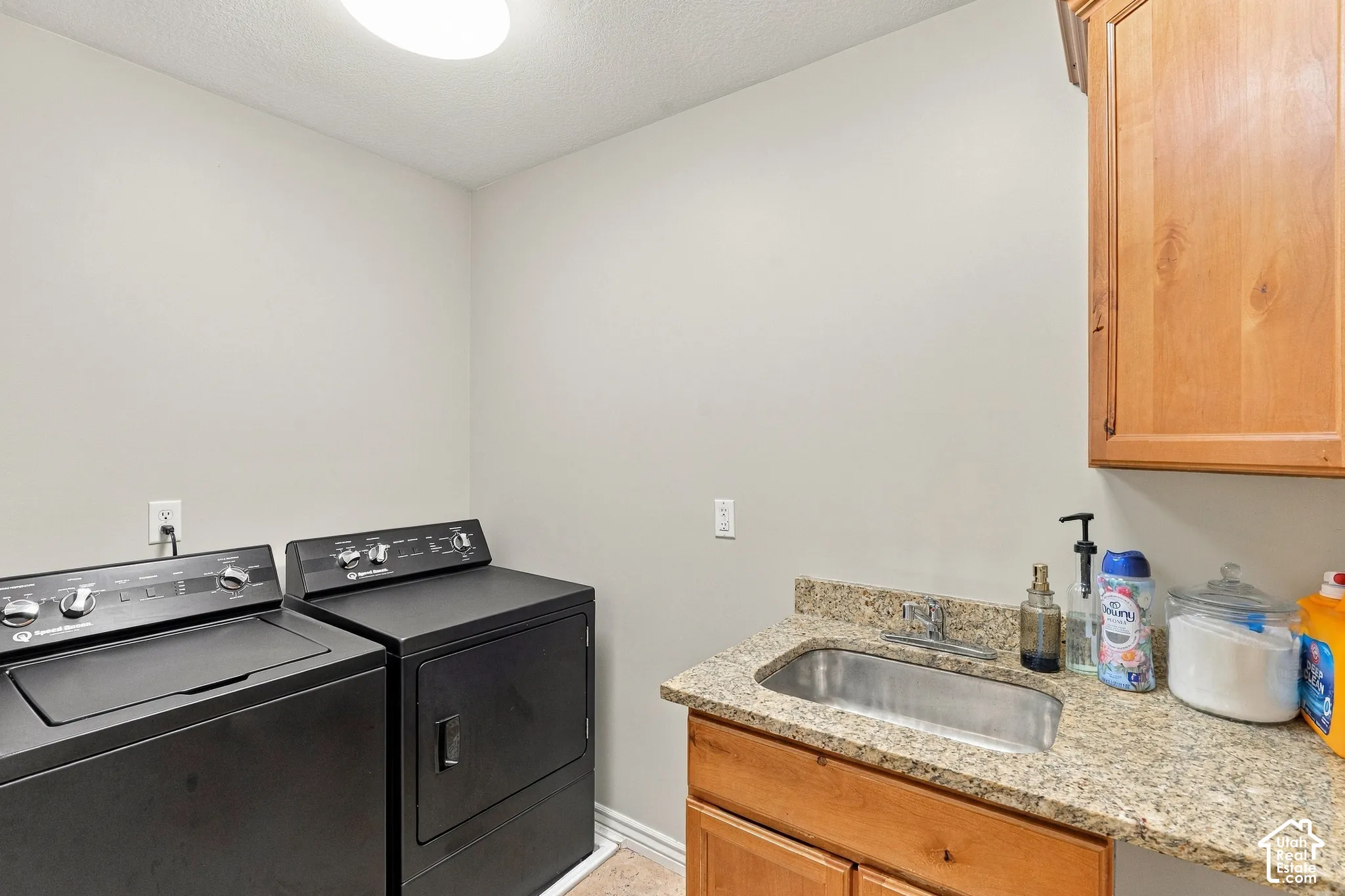 Built-in wood cabinetry, granite-finish countertop, undermount stainless steel sink, and overhead lighting