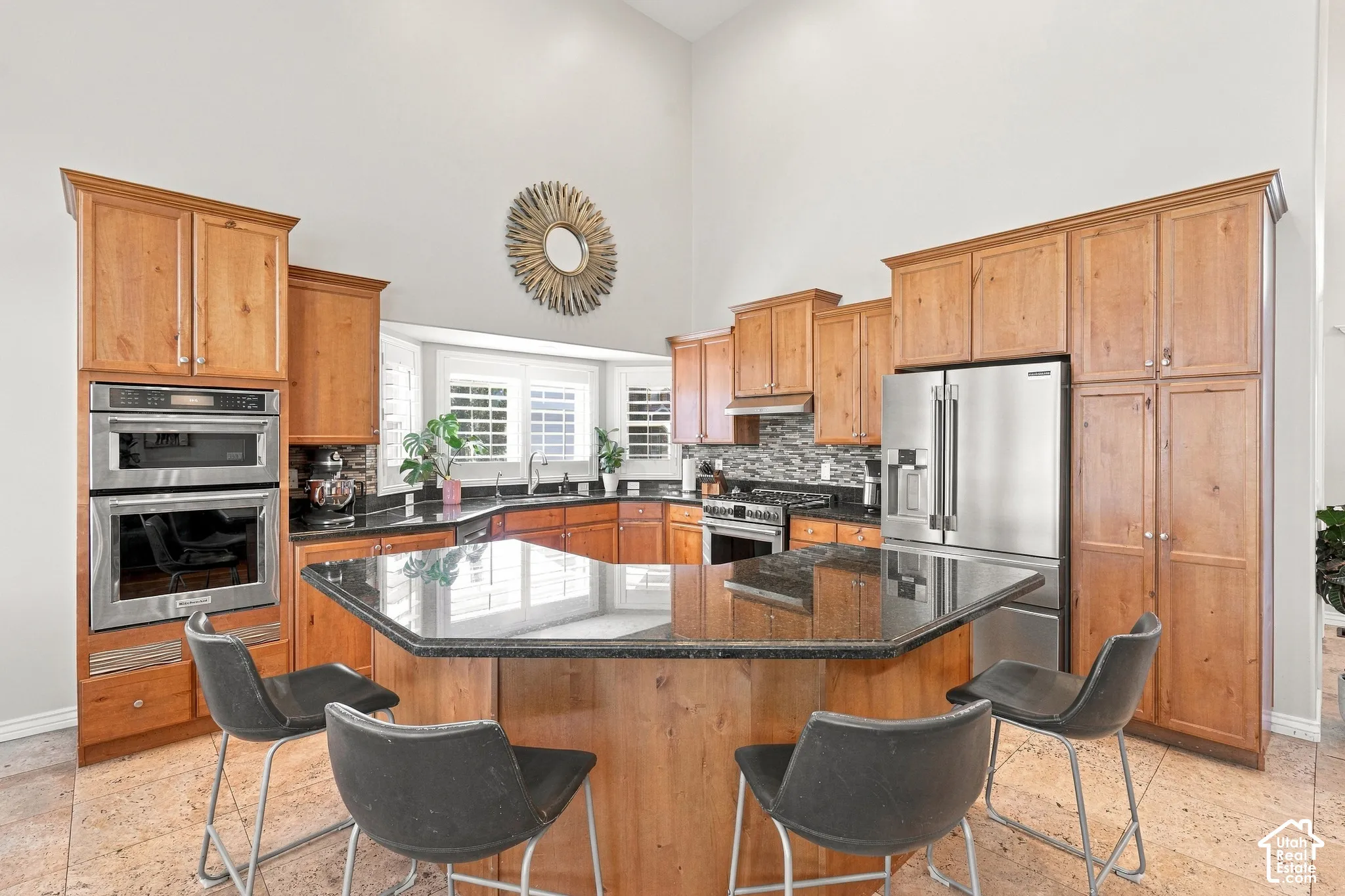 Kitchen featuring abundant wood cabinetry, stainless steel appliances, a center island with bar seating, dark countertops, and a tiled backsplash