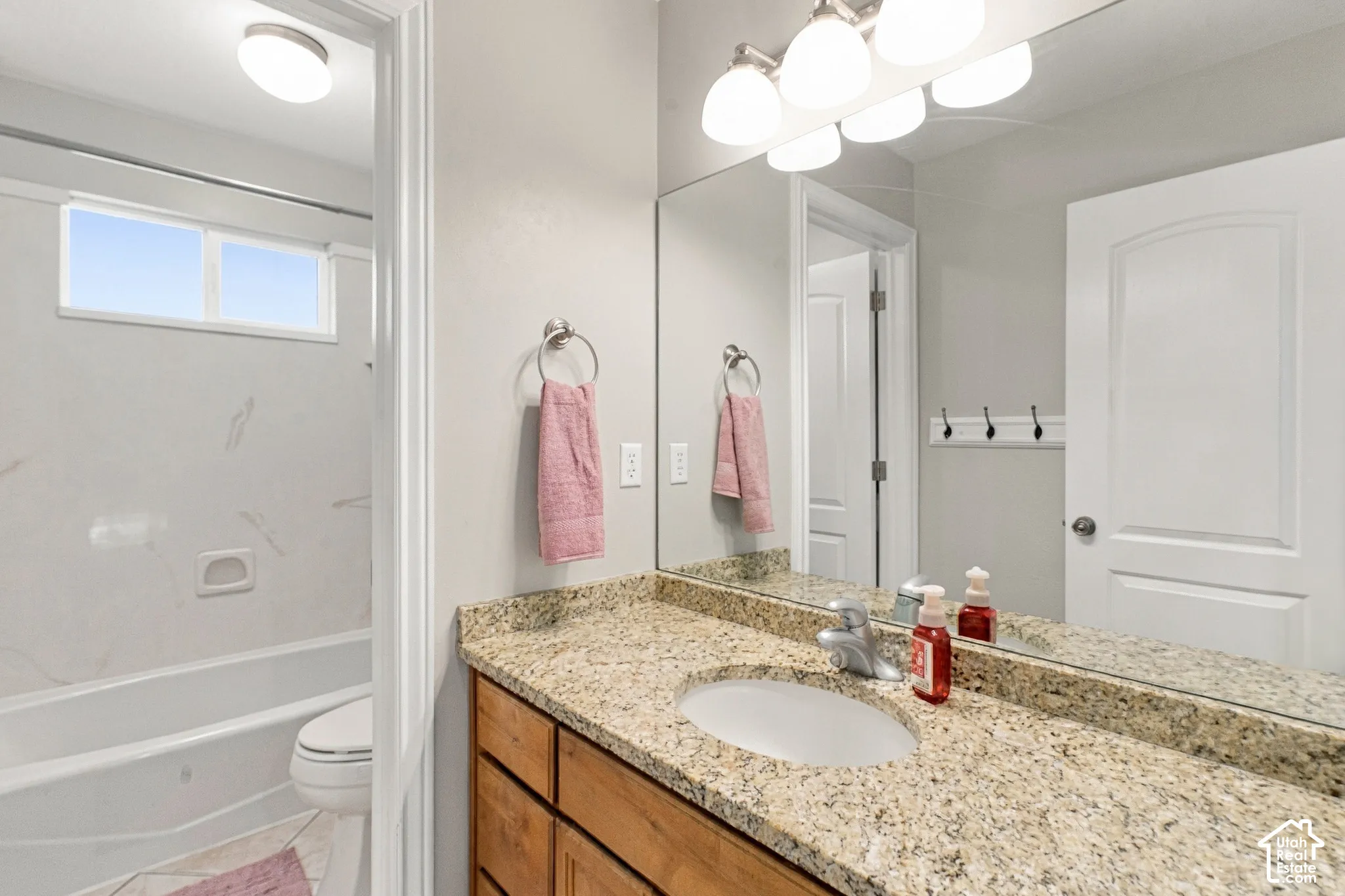 Vanity with granite countertop and integrated sink, chrome faucet, and wood-finish cabinetry