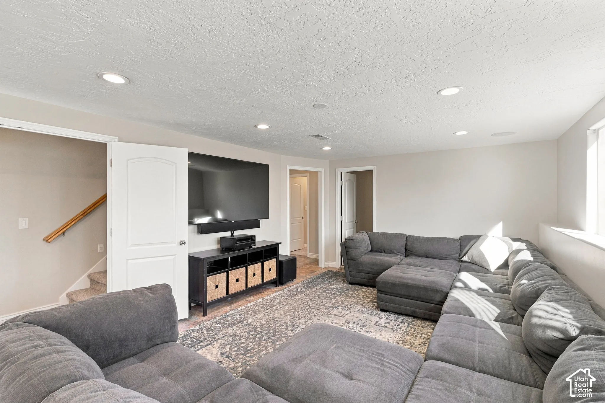 Spacious entertainment area with recessed lighting, light-colored walls, and a window for natural light