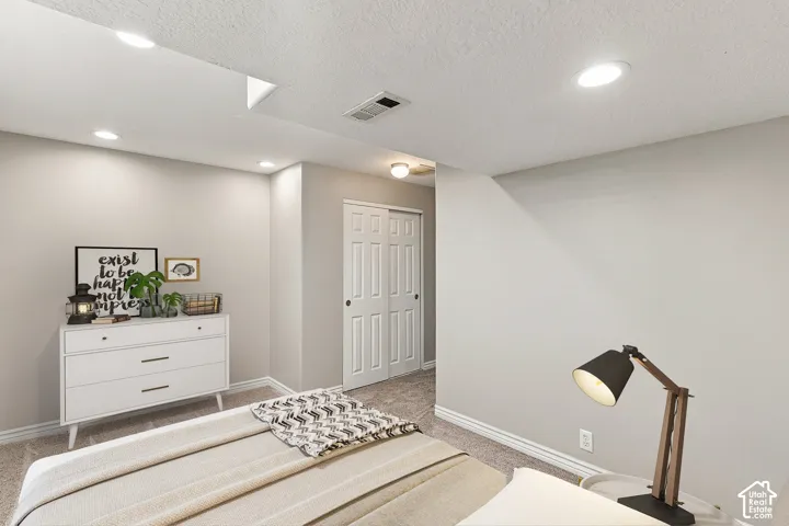 Recessed lighting, neutral wall paint, carpeted flooring, and a sliding two-panel door