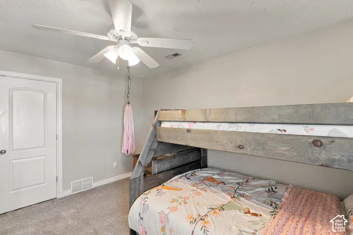 Neutral wall color, ceiling fan with integrated lighting, door with panel detailing, and gray carpet flooring