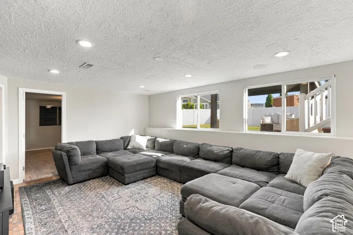 Recessed lighting illuminates this space featuring light gray walls, wood-finish flooring, and multiple windows