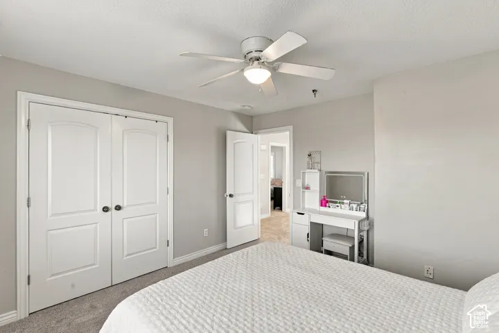 Carpeted flooring, white bi-fold doors with dark hardware, ceiling fan with integrated lighting, and neutral wall paint