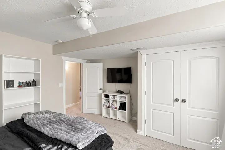 White ceiling fan with integrated lighting, built-in shelving, white paneled doors, and neutral carpet