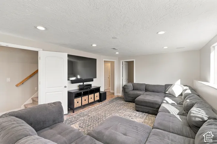 Spacious entertainment area with recessed lighting, light-colored walls, and a window for natural light