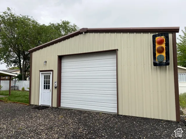 Metal building with a roll-up garage door, pedestrian entry door, and dark gravel ground cover