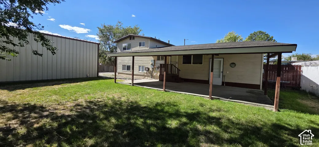 Expansive backyard featuring a covered patio, detached shop, and a wood privacy fence