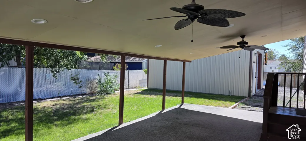 Covered patio with integrated ceiling fans and recessed lighting, featuring a concrete surface and direct access to a fenced yard