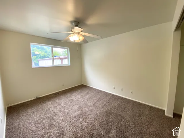 Neutral wall paint, brown carpet flooring, ceiling fan with integrated lighting, and a double-pane window