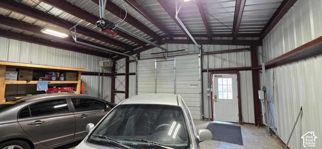 Metal framed structure with corrugated metal roofing, an overhead garage door, and a white entry door