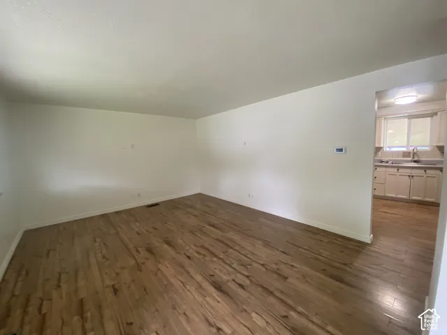 Wood-finish flooring throughout, white wall finishes, and a kitchen with light cabinetry