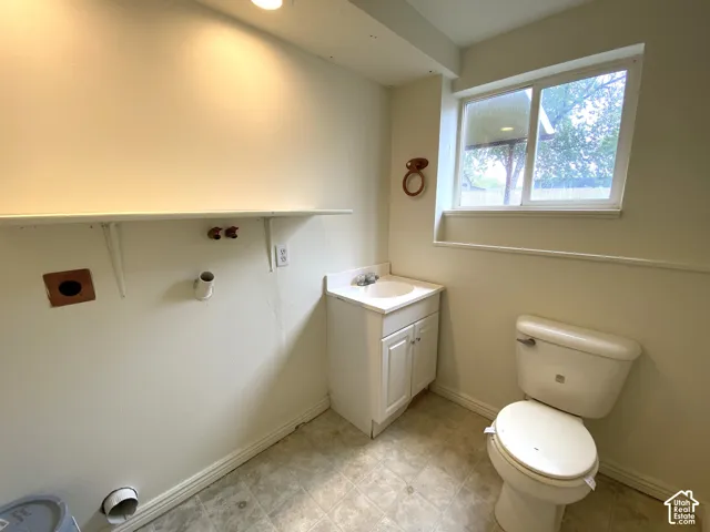 Recessed lighting, vinyl flooring, white vanity with integrated sink, dual-pane window, and white toilet